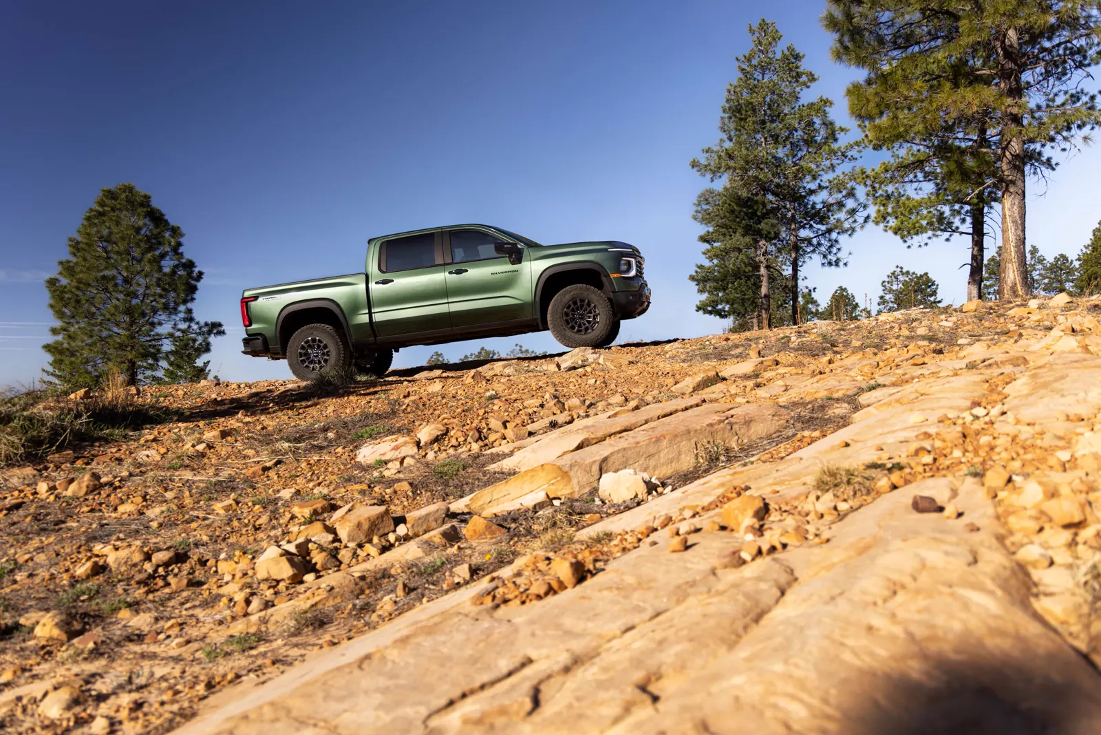Green 2027 Chevrolet Silverado Trail Boss pickup on a rocky hillside