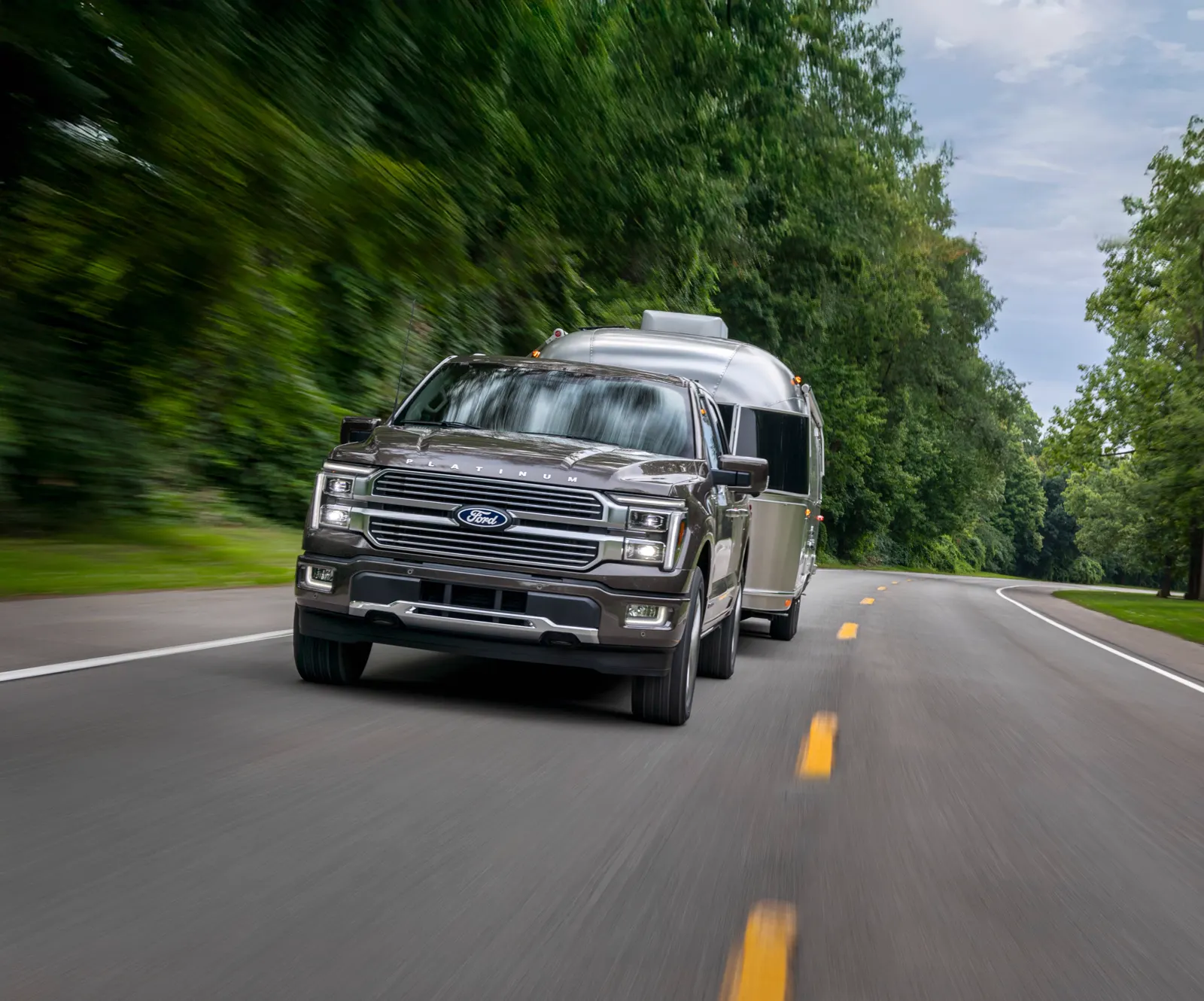 Ford F-150 pickup towing a travel trailer on a two-lane road